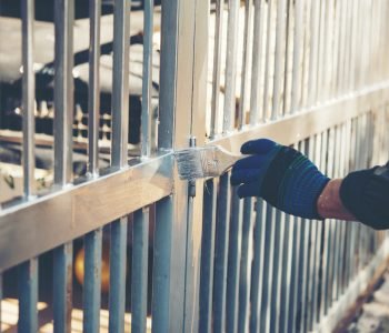 Construction worker painting fence at home, closeup